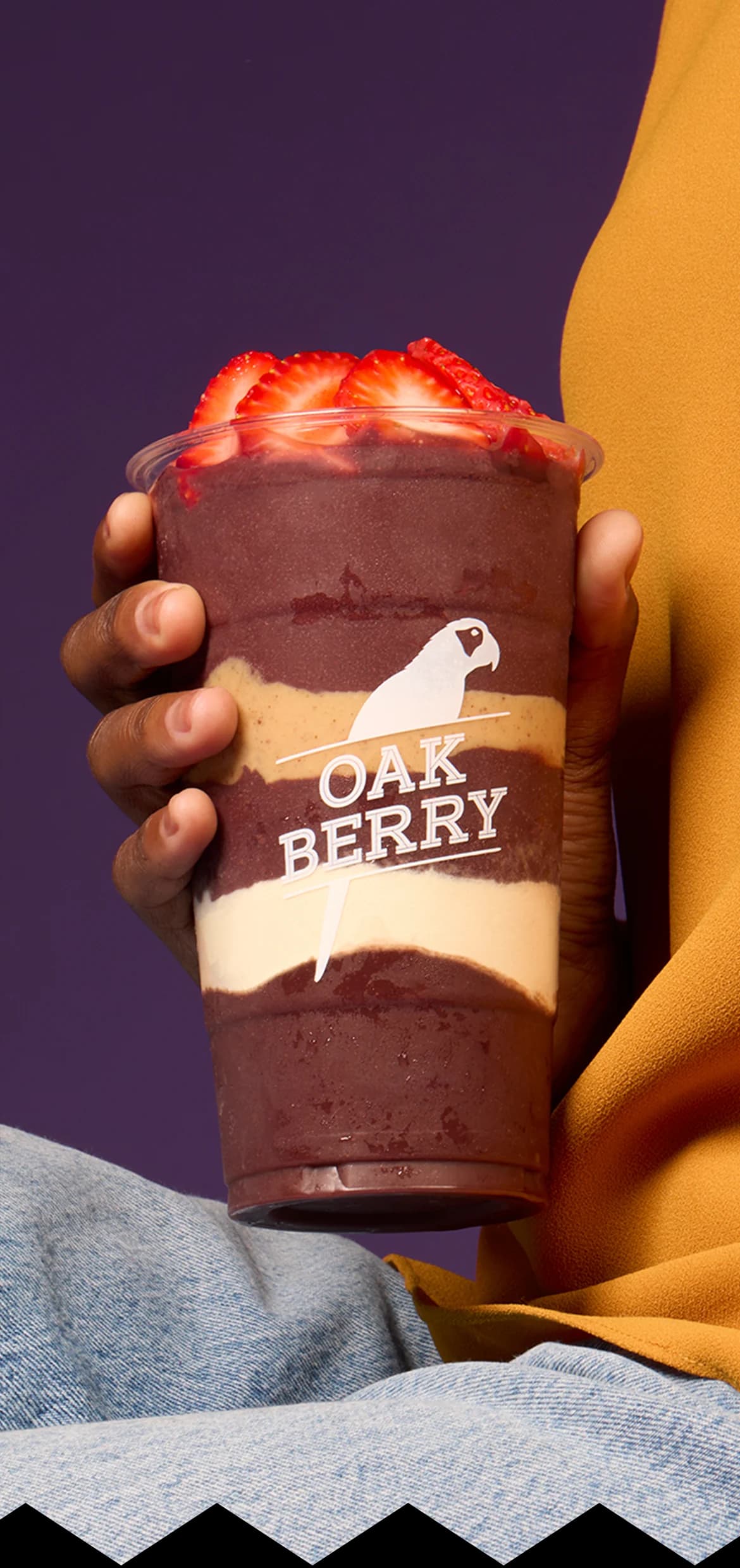 A hand holding an OAKBERRY bowl
